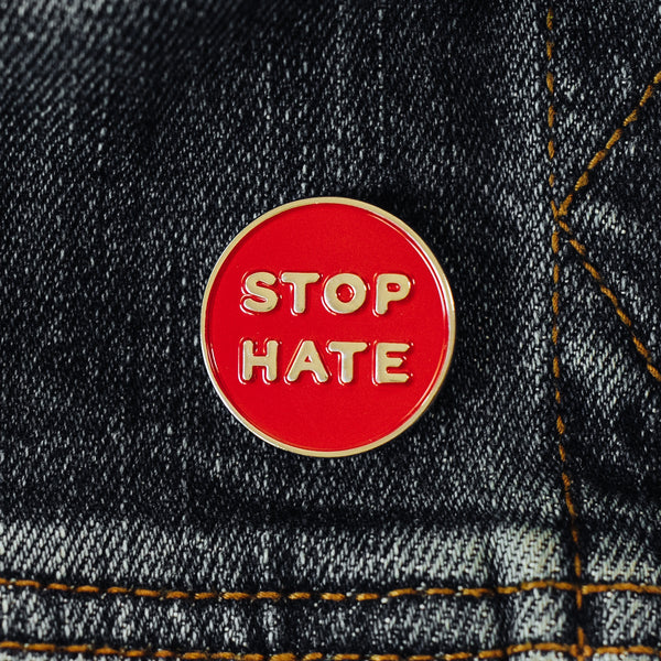 Stop hate enamel pin on a jean jacket