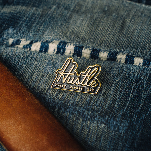 hustle enamel pin for entrepreneurs with brown belt and denim jeans